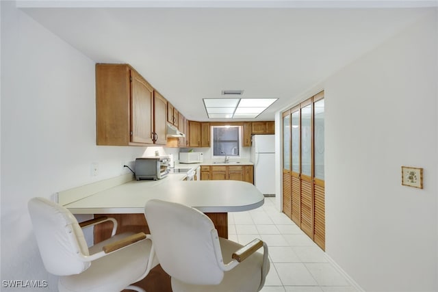 kitchen featuring white appliances, brown cabinets, a peninsula, light countertops, and a sink