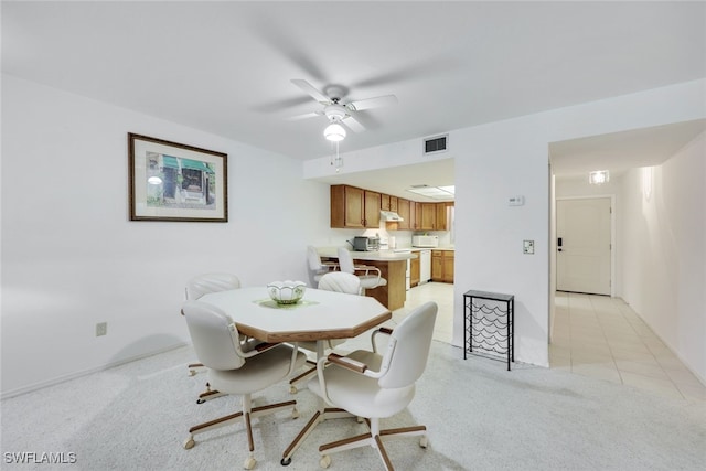 dining space with visible vents, ceiling fan, light carpet, and light tile patterned flooring