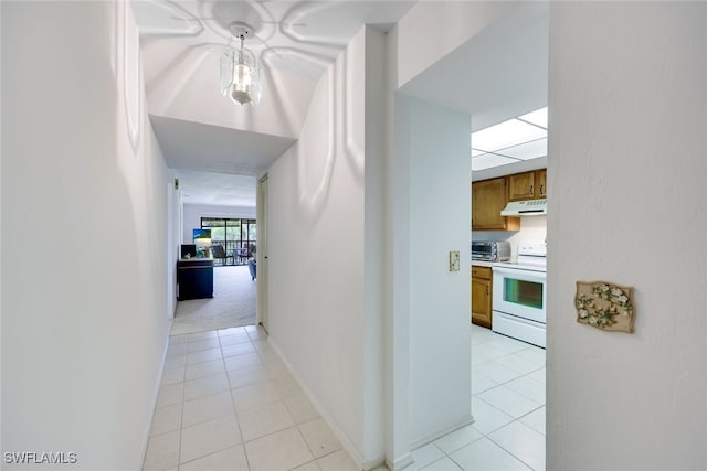 hallway with a toaster, baseboards, and light tile patterned floors