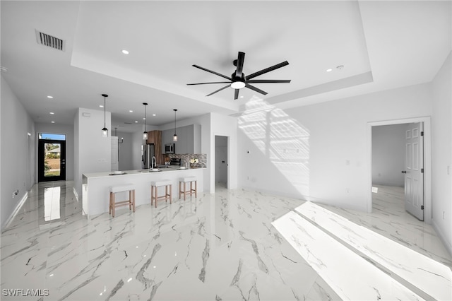 unfurnished living room with a raised ceiling and ceiling fan