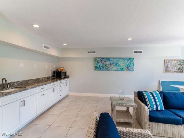 kitchen featuring dark stone countertops, sink, white cabinets, and light tile patterned flooring