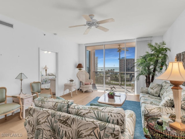 living room with wood-type flooring, floor to ceiling windows, and ceiling fan