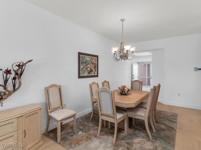 dining area with dark hardwood / wood-style flooring and an inviting chandelier