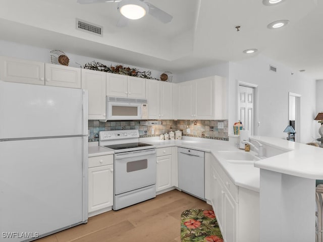 kitchen featuring white cabinetry, white appliances, kitchen peninsula, and sink