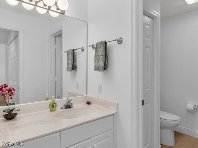 bathroom with hardwood / wood-style flooring, vanity, and toilet