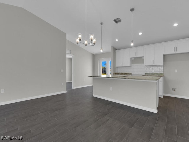 kitchen featuring an island with sink, lofted ceiling, pendant lighting, and white cabinets