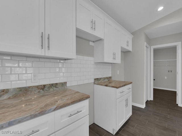 kitchen featuring tasteful backsplash, light stone countertops, and white cabinets