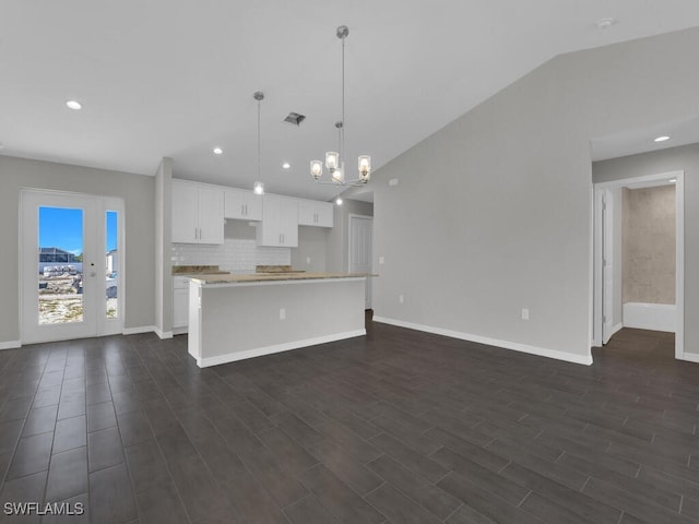 kitchen with pendant lighting, dark hardwood / wood-style floors, white cabinets, a kitchen island, and vaulted ceiling