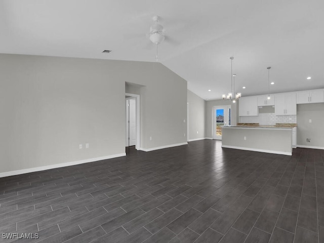 unfurnished living room featuring lofted ceiling, ceiling fan with notable chandelier, and dark hardwood / wood-style flooring