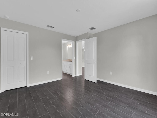 unfurnished bedroom featuring dark wood-type flooring, connected bathroom, and a closet