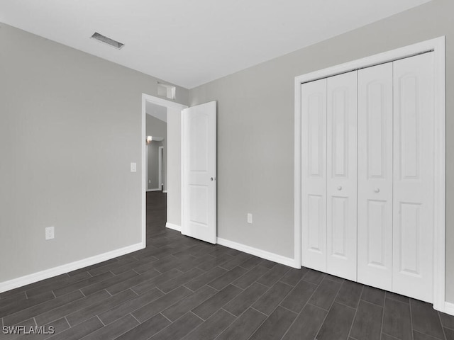 unfurnished bedroom with dark wood-type flooring and a closet