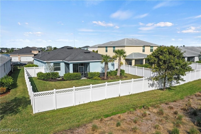 back of property with a yard, a fenced backyard, and a residential view