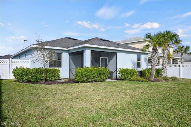 rear view of house featuring a yard and a sunroom