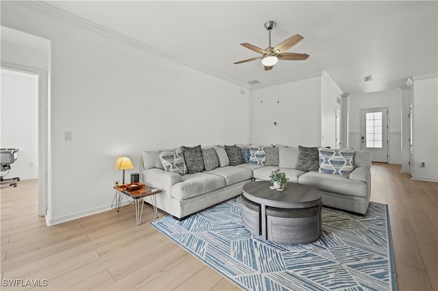 living area with crown molding, baseboards, light wood-style floors, and ceiling fan