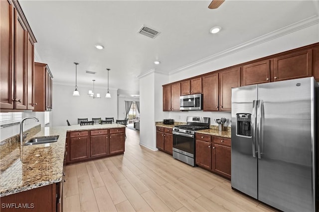 kitchen featuring visible vents, ornamental molding, a sink, a peninsula, and appliances with stainless steel finishes