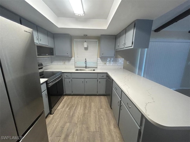 3926 Palm Tree Blvd, Cape Coral, FL 33904 - kitchen featuring appliances with stainless steel finishes, gray cabinetry, a raised ceiling, tasteful backsplash, and light wood-style floors