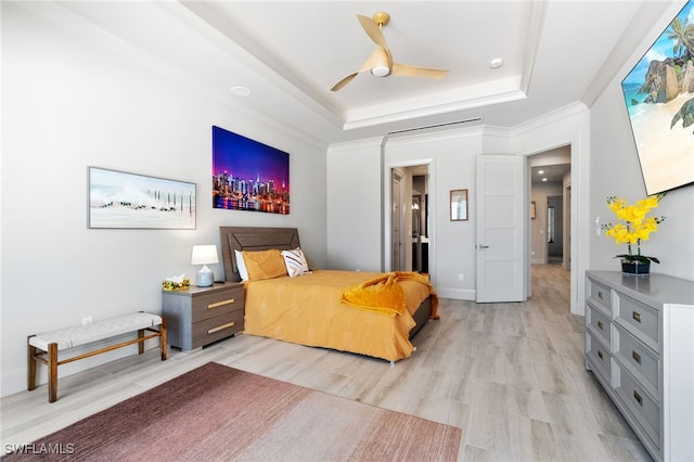 bedroom with a tray ceiling, baseboards, light wood-style flooring, and ornamental molding