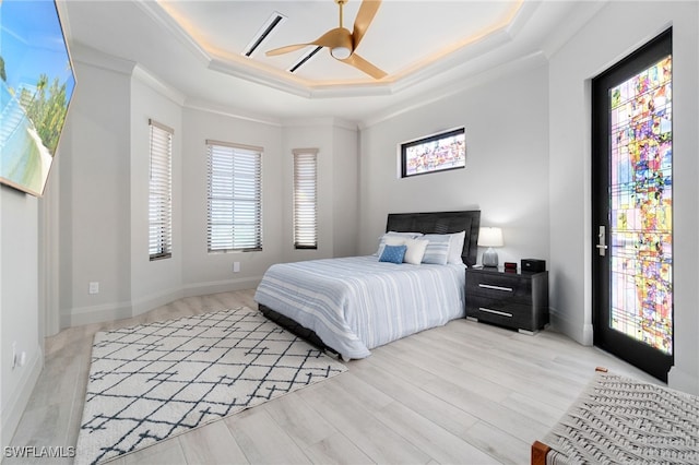 bedroom featuring light wood-type flooring, ornamental molding, a raised ceiling, ceiling fan, and access to exterior