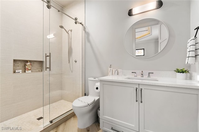 bathroom with wood finished floors, toilet, a stall shower, and vanity