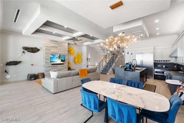 dining area featuring coffered ceiling, sink, beam ceiling, and light hardwood / wood-style flooring