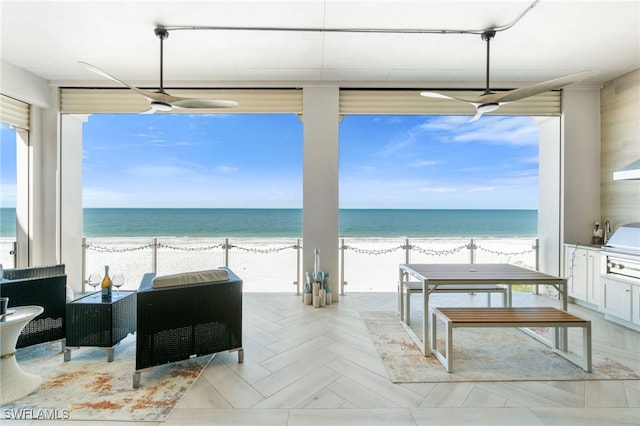 interior space with a view of the beach, a water view, a grill, and exterior kitchen