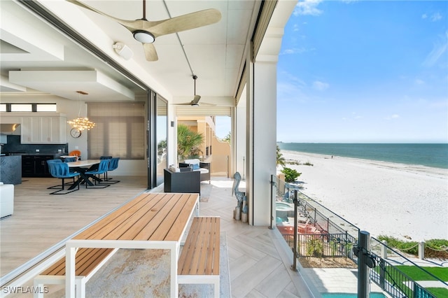 balcony featuring a water view, ceiling fan, and a beach view