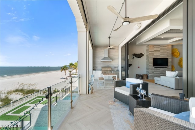 balcony with a water view, a beach view, area for grilling, an outdoor hangout area, and an outdoor kitchen