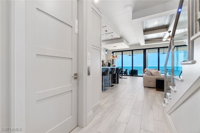 corridor with a water view, coffered ceiling, and beam ceiling