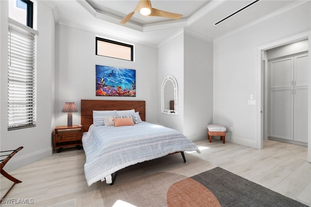 bedroom featuring a raised ceiling, ornamental molding, a ceiling fan, light wood-style floors, and baseboards