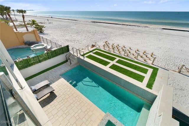 view of swimming pool featuring a view of the beach, a fenced in pool, a water view, and a patio