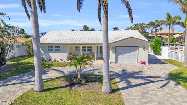 ranch-style house with a garage, decorative driveway, and metal roof