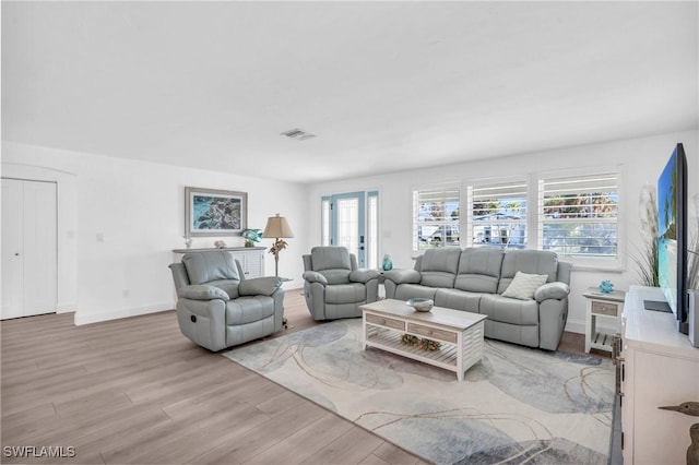 living room featuring light wood-style floors, visible vents, and baseboards