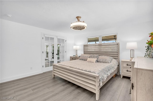 bedroom with multiple windows, wood-type flooring, access to exterior, and french doors