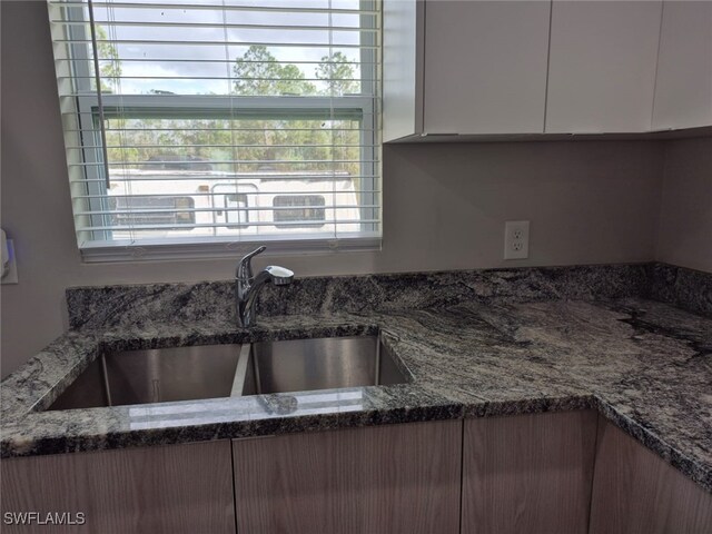 kitchen with white cabinetry, stone countertops, sink, and plenty of natural light