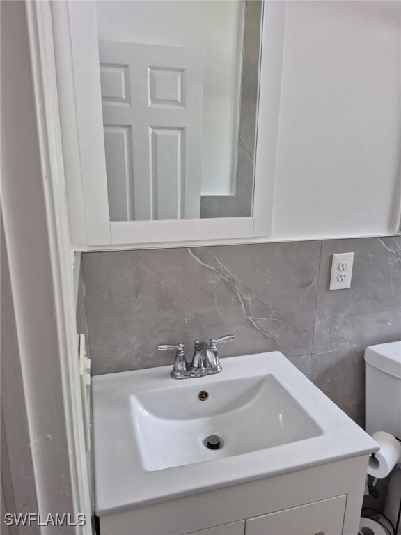 bathroom featuring vanity, toilet, and backsplash