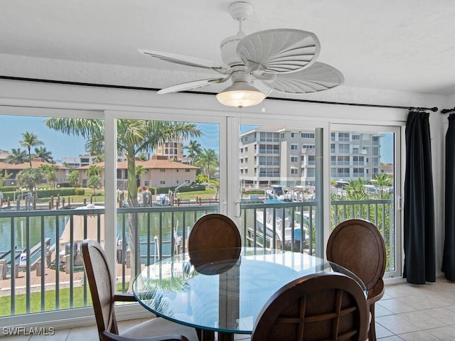 sunroom / solarium with ceiling fan and a water view