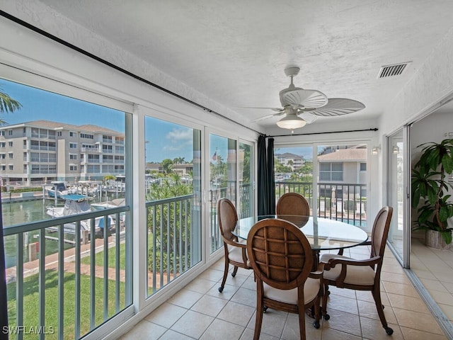 sunroom featuring a water view and ceiling fan