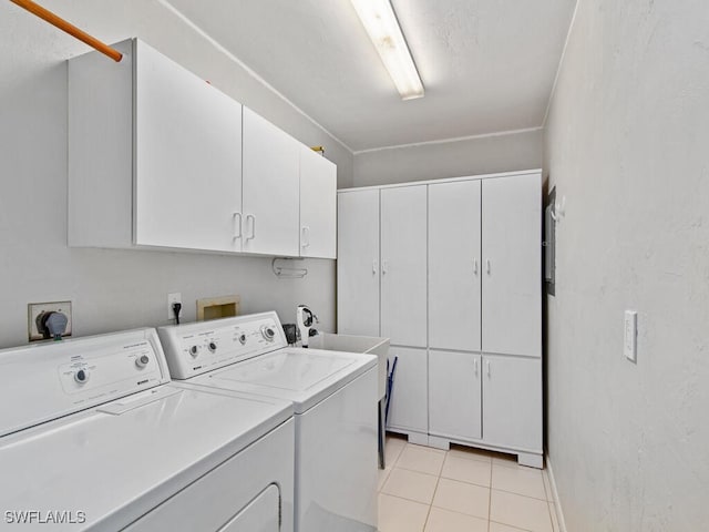 laundry room featuring cabinets, light tile patterned floors, and washing machine and clothes dryer