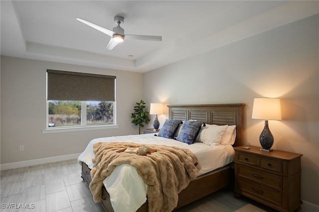 bedroom with ceiling fan and a tray ceiling