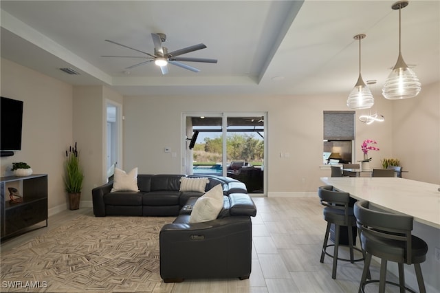 living room featuring ceiling fan and a tray ceiling