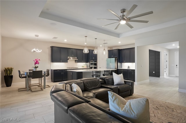 living room with a tray ceiling and ceiling fan