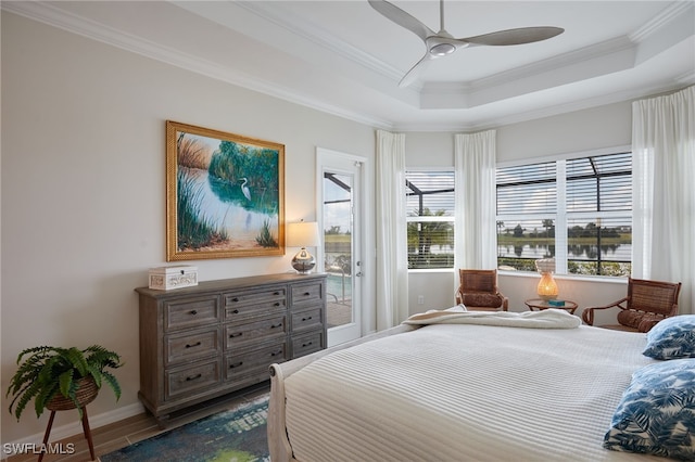 bedroom with ornamental molding, a tray ceiling, hardwood / wood-style flooring, ceiling fan, and access to exterior