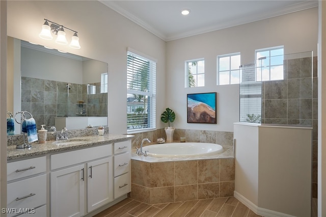 bathroom featuring a healthy amount of sunlight, ornamental molding, separate shower and tub, and vanity