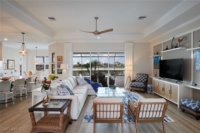 living room with crown molding, a tray ceiling, ceiling fan, and light hardwood / wood-style flooring