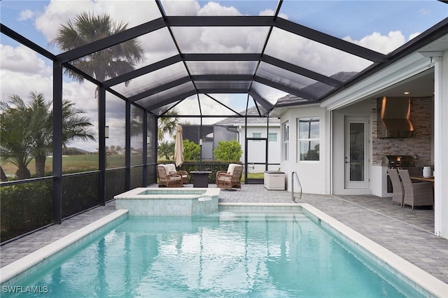 view of swimming pool featuring a lanai, exterior kitchen, a patio area, area for grilling, and an in ground hot tub