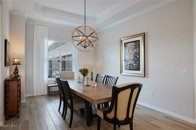 dining room featuring a notable chandelier, light hardwood / wood-style floors, and a raised ceiling