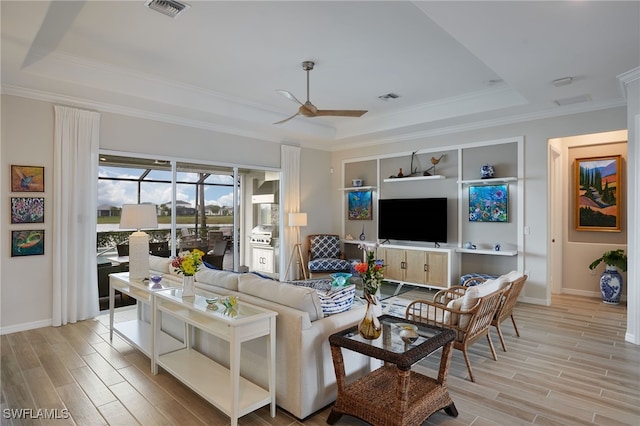 living room featuring a raised ceiling, ceiling fan, and light wood-type flooring