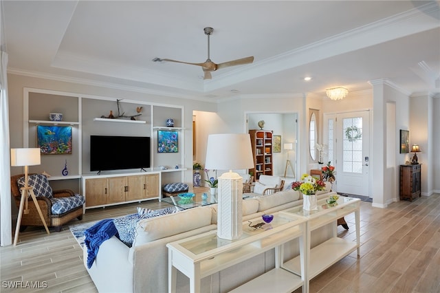 living room featuring crown molding, ceiling fan, a raised ceiling, and light hardwood / wood-style floors