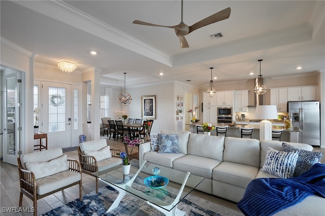 living room with crown molding, light wood-type flooring, and a tray ceiling