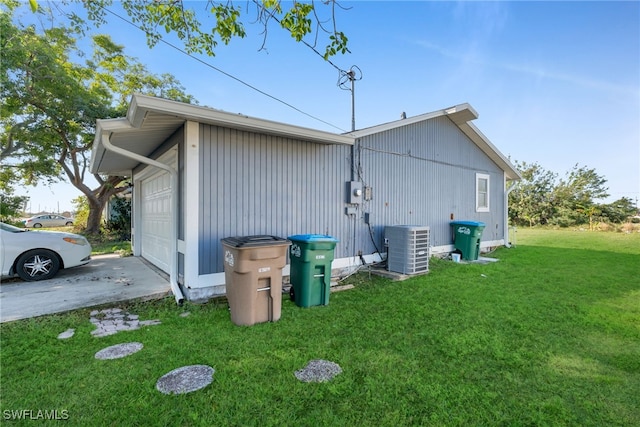 view of side of home with central AC unit, a yard, and a garage